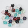 A collection of irregular square geometric glass beads in various colors including black, pink, green, and clear.