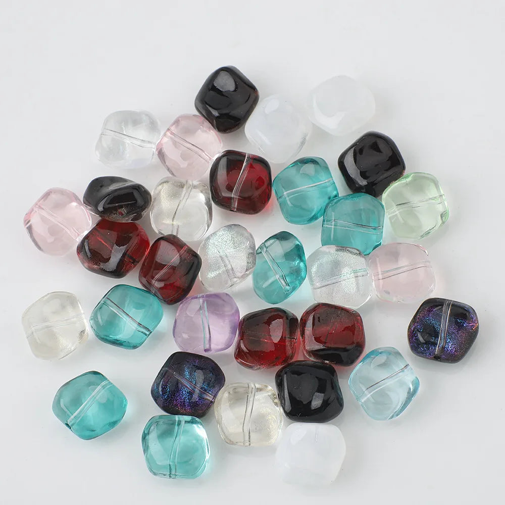 A collection of irregular square geometric glass beads in various colors including black, pink, green, and clear.