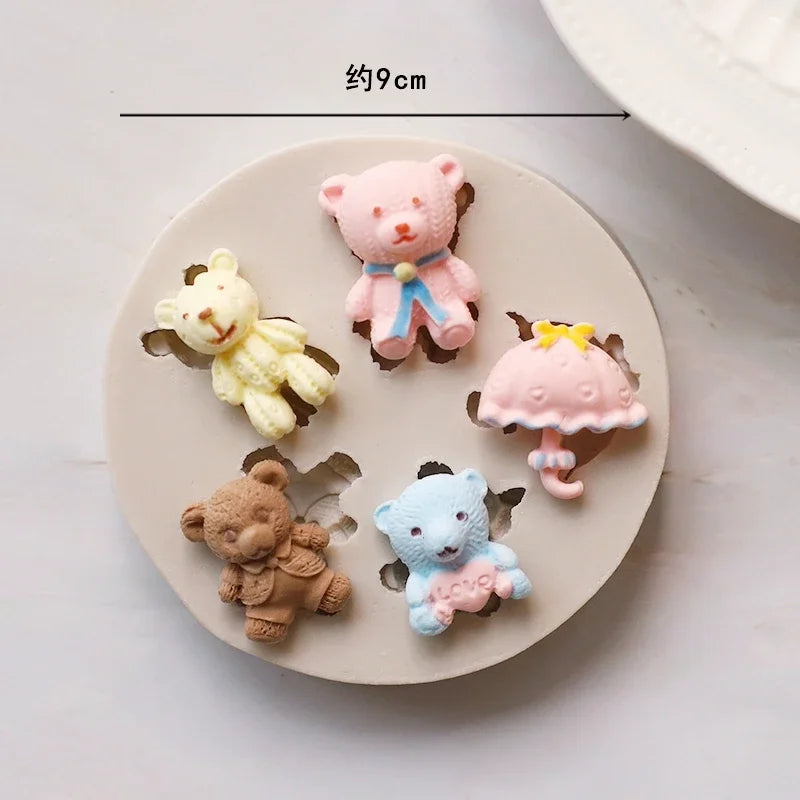 A set of silicone baby-themed cake molds including teddy bears, a pink bear, and a pink umbrella.