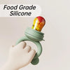 A hand is holding a light green silicone fruit feeder set with a colorful fruit mold.