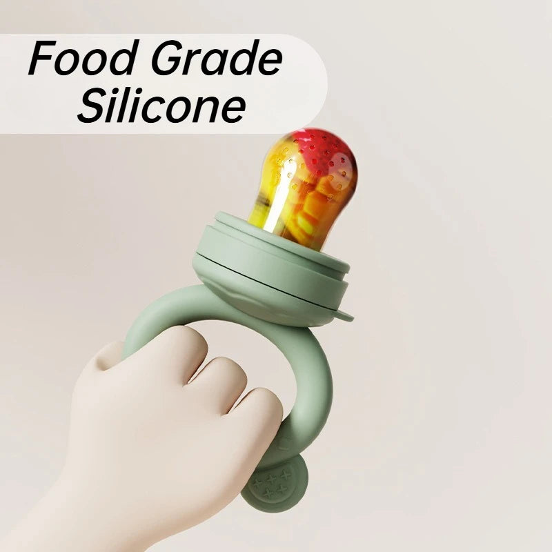 A hand is holding a light green silicone fruit feeder set with a colorful fruit mold.