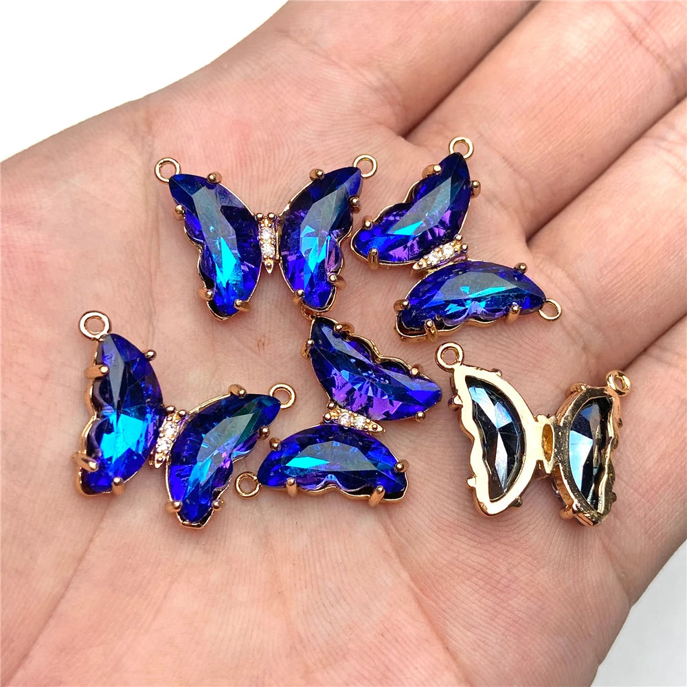 Gold-toned crystal butterfly charm beads displayed on a hand.