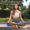 A woman sits meditating with a set of brass Tibetan singing bowls on a yoga mat outdoors.