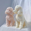 Two fluffy poodle dog silicone candle molds in pink and cream colors sitting on white fabric