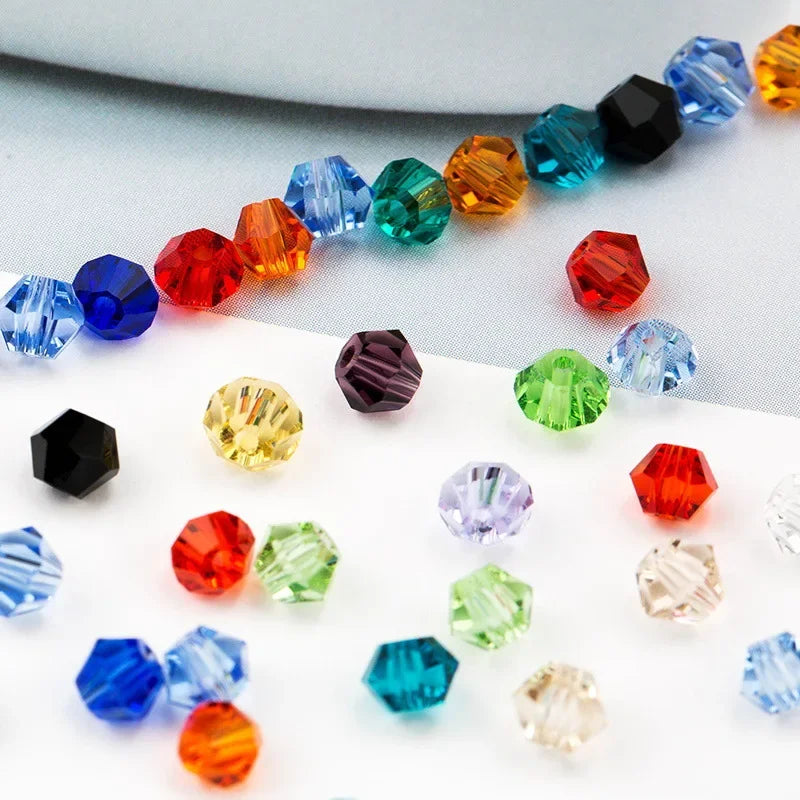A collection of multicolored faceted glass crystal beads in various shapes and colors arranged in a diagonal line.
