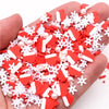 A hand holds a pile of red and white heart-shaped polymer clay slices decorated with white snowflake patterns.