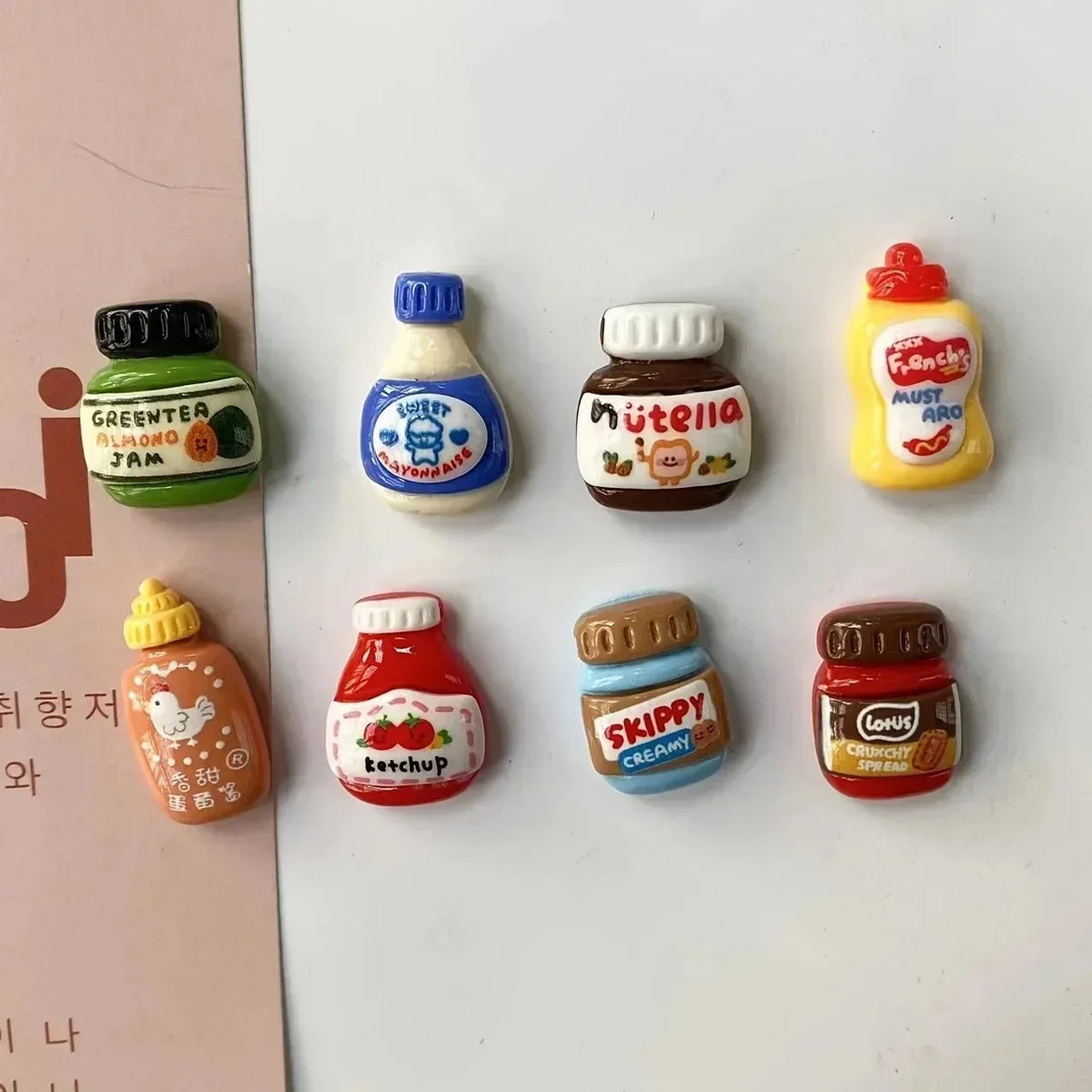 A set of eight colorful kawaii jam jar fridge magnets featuring various fruit and food themes.