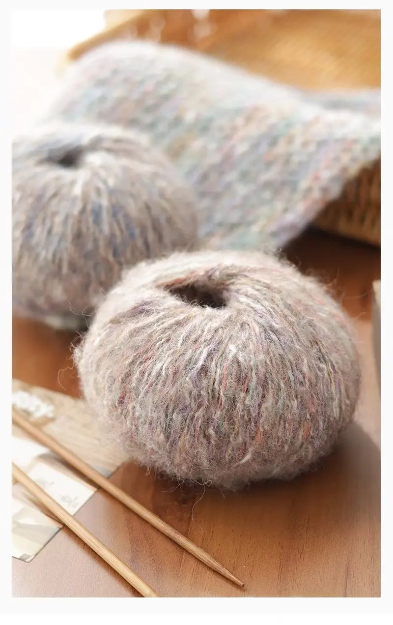 A ball of soft gray alpaca blend yarn resting on a wooden surface next to knitting needles.