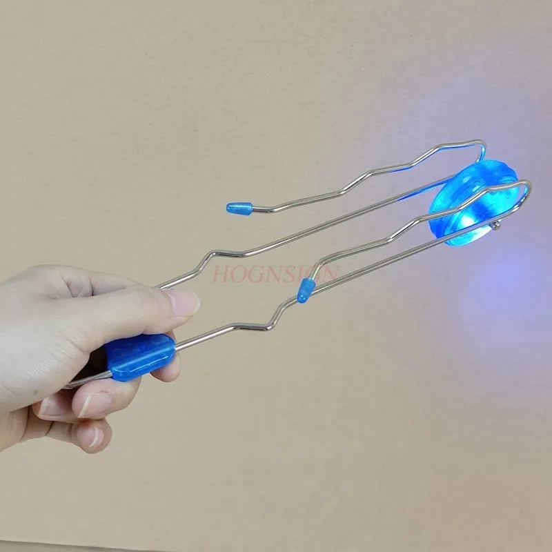 A hand holds a retro magic rail twirler toy with a blue light, demonstrating its flexible metal structure.