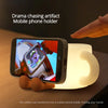 A mobile phone holder made from a coffee cup shaped night light, illuminating the device.