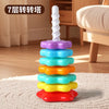 A colorful rainbow stacking tower toy made of plastic rings and a white spire for toddlers.