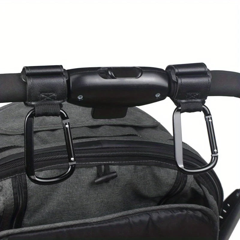 Close-up of black heavy-duty stroller hooks attached to a dark gray fabric bag or carrier.