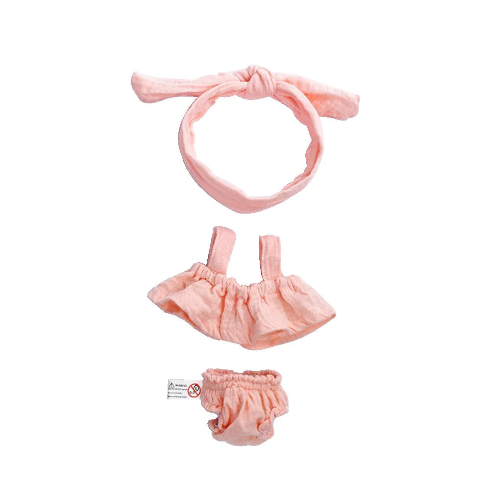 A pink 3-piece doll outfit set for a baby doll, including a headband, a ruffled top, and bottoms.