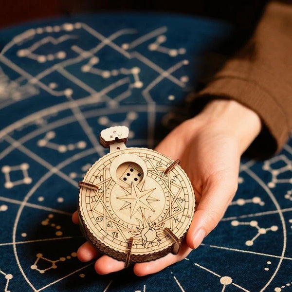 Une main tient un puzzle de dés en bois avec des engrenages complexes et des marques sur une surface bleu foncé.