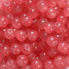 A close-up view of small, round, translucent pink glass beads for DIY jewelry making.