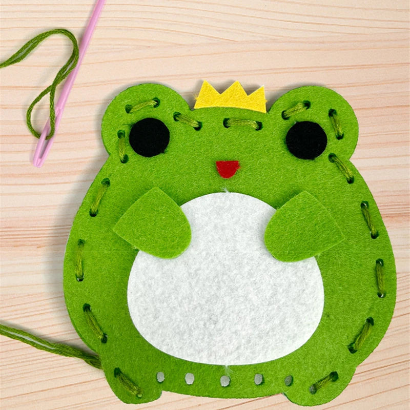 A bright green felt frog craft with a yellow crown and black eyes, used as a beginner-friendly DIY sewing kit for kids.