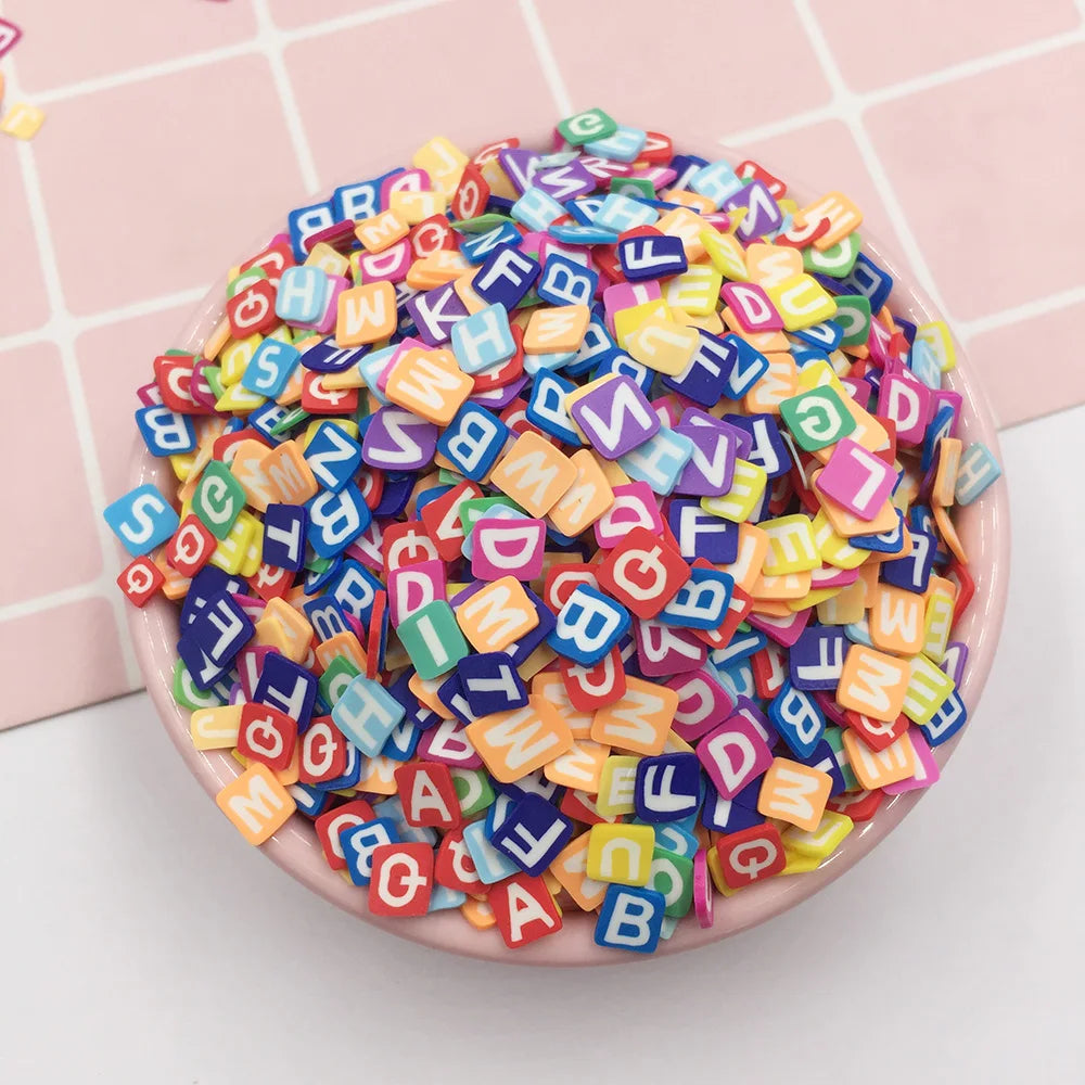 A pile of colorful polymer clay letter sprinkles in various shapes and colors on a pink plate.
