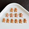 A white oval dish holds thirty small gingerbread man resin charms with red and green accents.