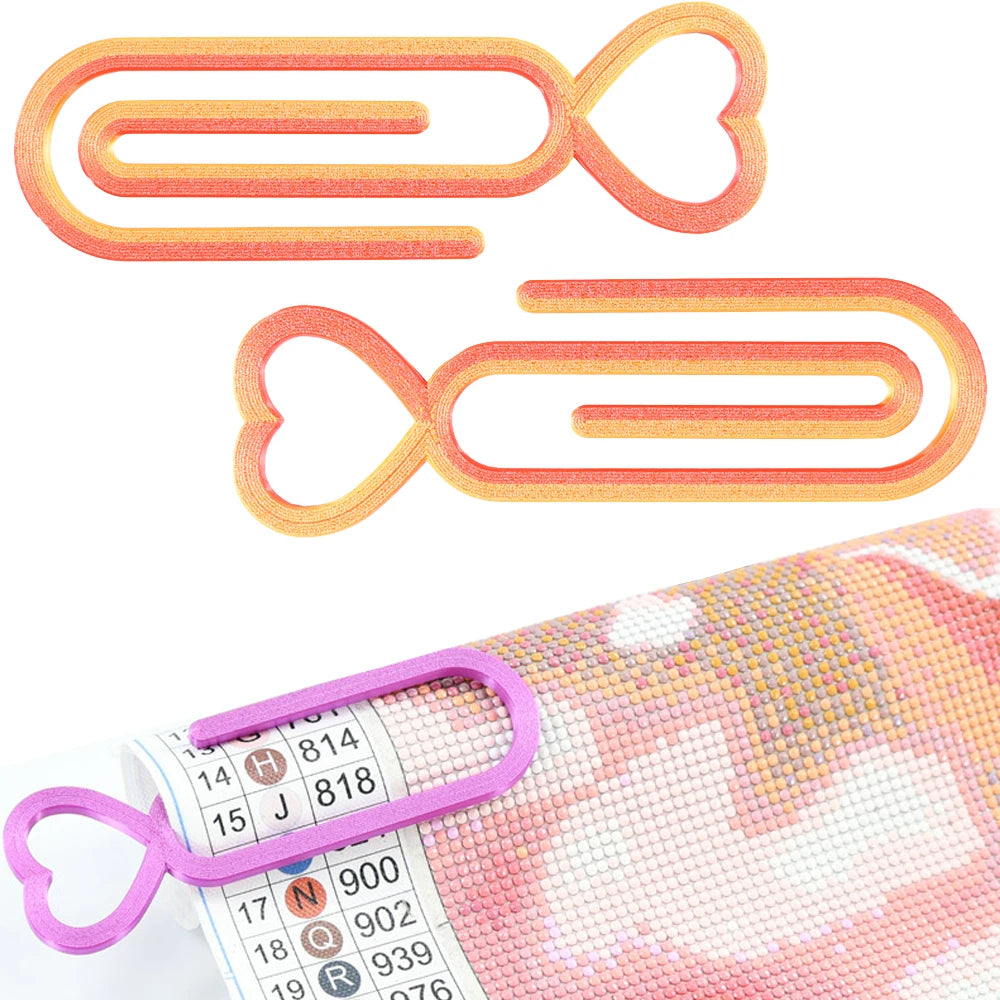 Two orange and pink heart-shaped clips for diamond painting canvas