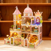 A detailed wooden dollhouse kit of a castle featuring pink and white architecture with LED lighting and furniture.