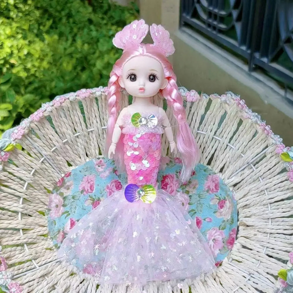 A pink sequin mermaid doll with a tulle wedding dress is displayed in a woven basket.