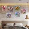 A bedroom wall decorated with framed floral paintings above a bed.