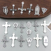 A collection of vintage antique silver cross charms and pendants for jewelry making displayed on a dark wooden surface.