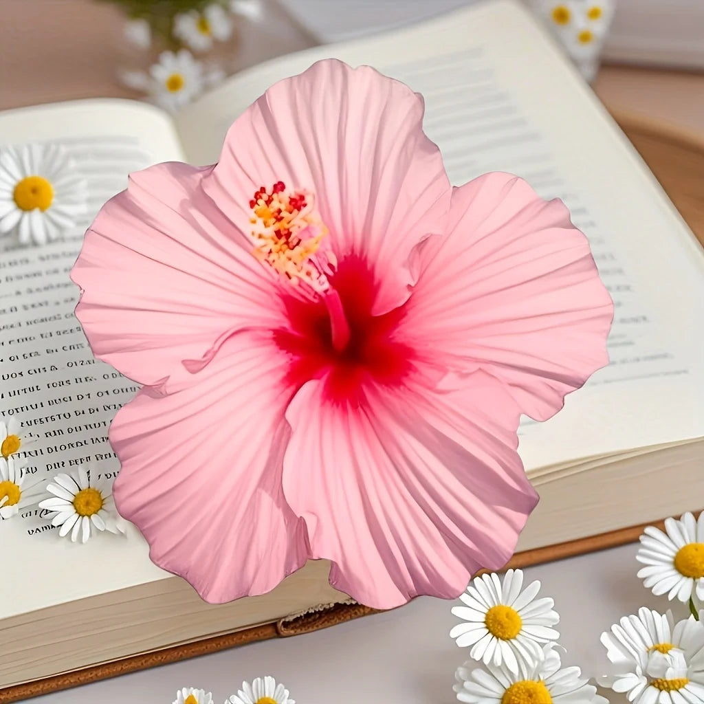 Pink hibiscus flower silicone mold set resting on an open book with white daisies.