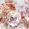 A collection of pink and orange butterfly stickers scattered on lace fabric and parchment paper.