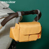 A yellow leather bottle holder is attached to a stroller handlebar.