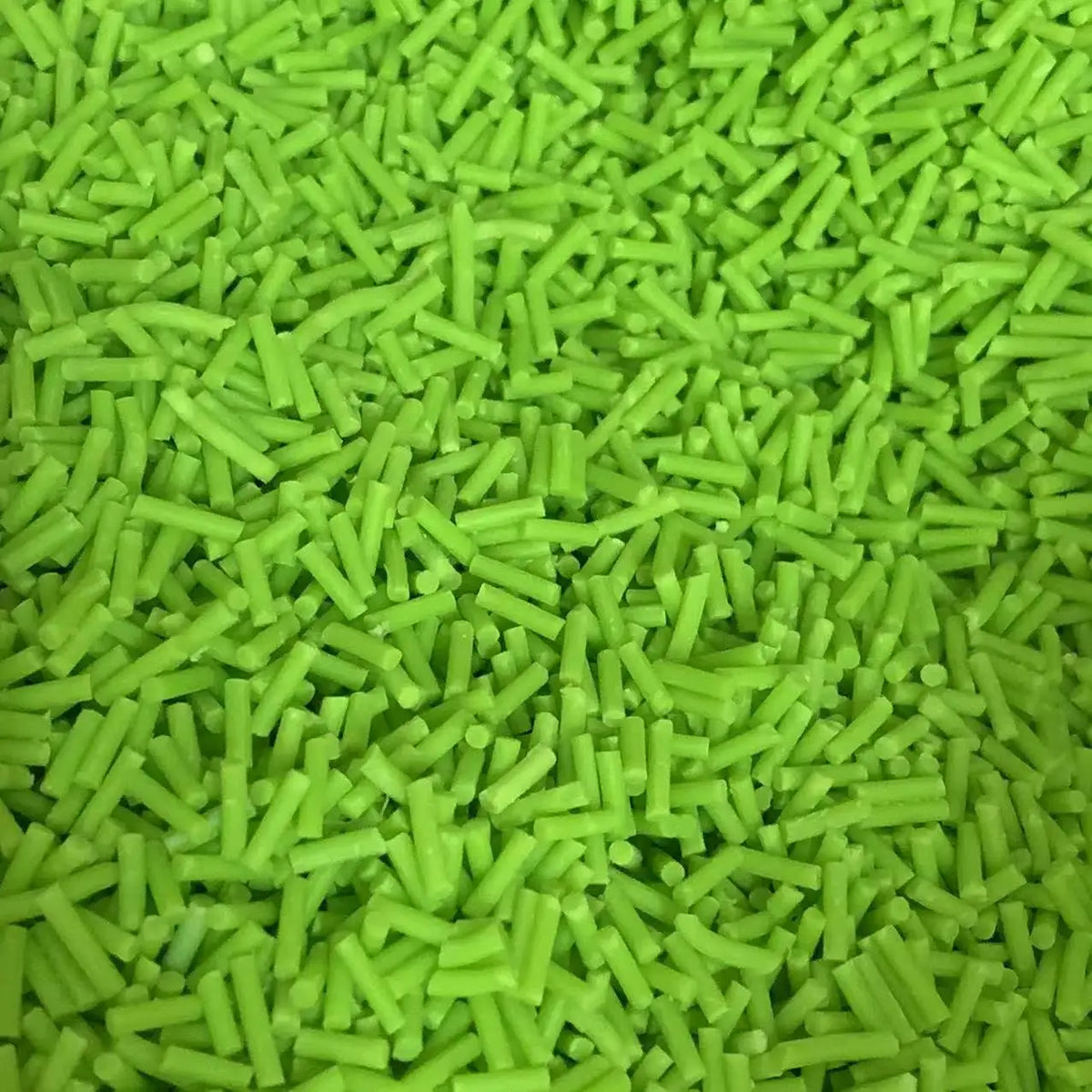 A pile of bright lime green soft polymer clay candy sprinkles for cake decorating.