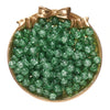 A pile of green glass crackle beads for jewelry making displayed in a gold-toned dish with a bow.