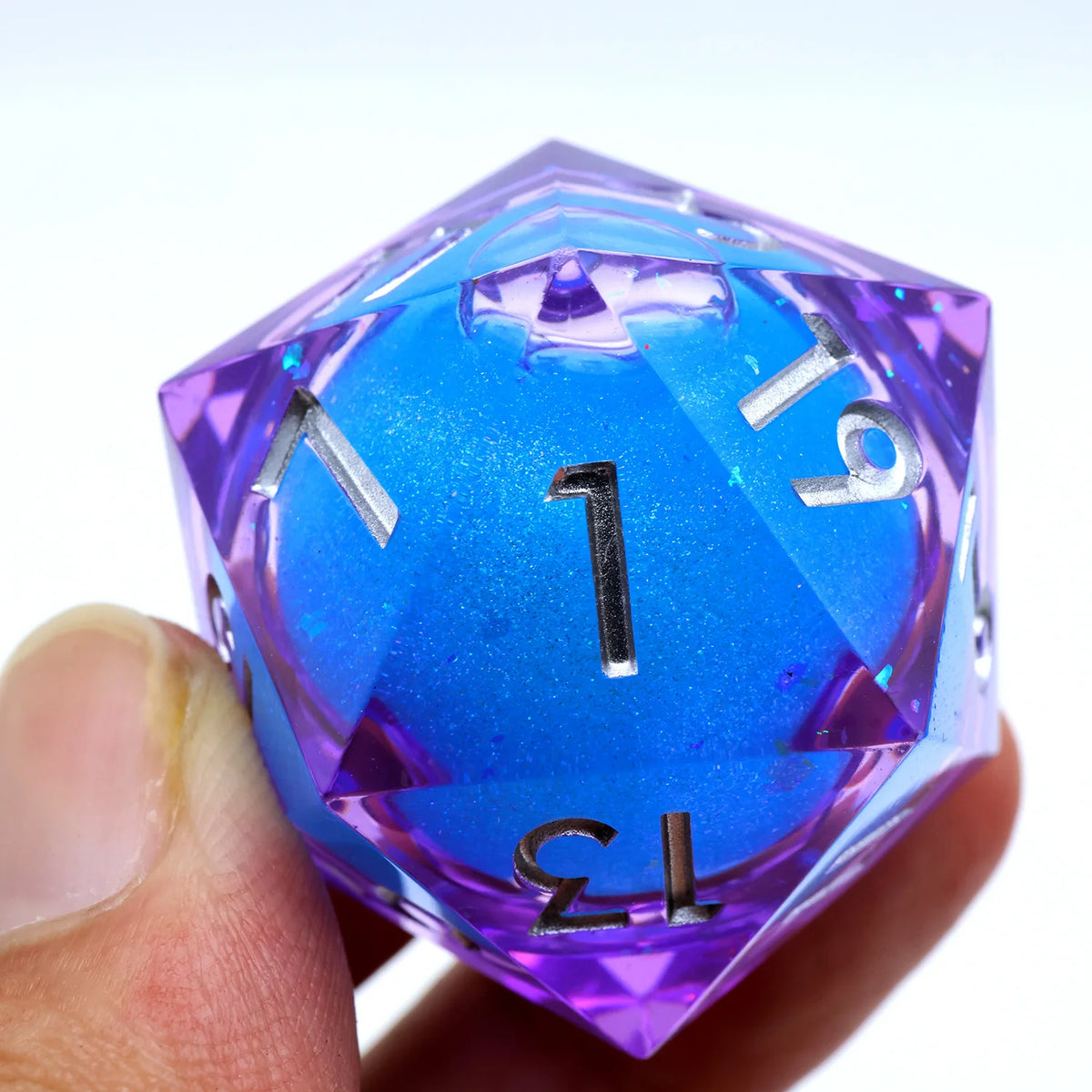 A hand holds a large, translucent purple and blue resin D20 die with a liquid swirl pattern.