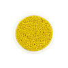 A circular plastic container filled with bright yellow Czech glass seed beads for jewelry making
