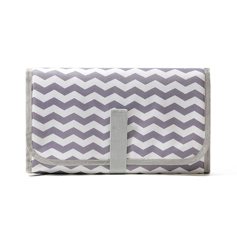 A purple and white chevron patterned portable waterproof baby changing mat with a gray carry handle.