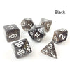 A set of seven black polyhedral acrylic dice, including d6s and d10s, scattered on a white surface.