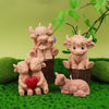 A set of four silicone candle molds shaped like Highland cows, sitting on green moss.