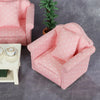 A pink 1:12 scale mini sofa and pillow set with white polka dots placed on a gray surface.