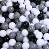 A close-up view of a large collection of colorful play balls in various shades of black, white, and gray.