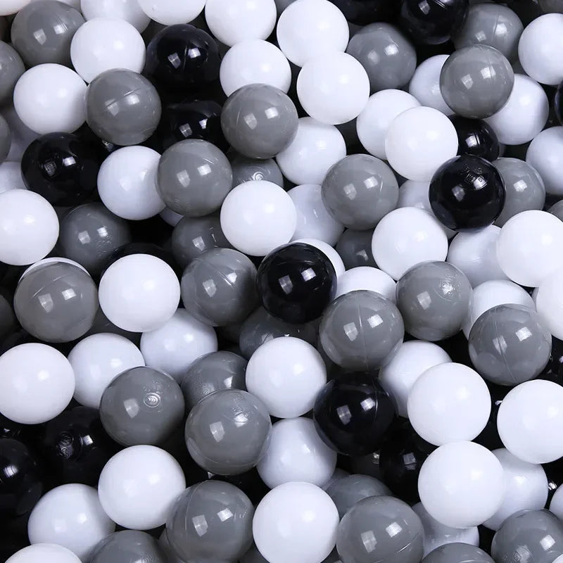 A close-up view of a large collection of colorful play balls in various shades of black, white, and gray.