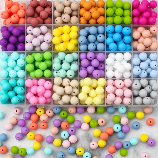 A collection of colorful silicone beads in various shades and sizes arranged in small compartments.