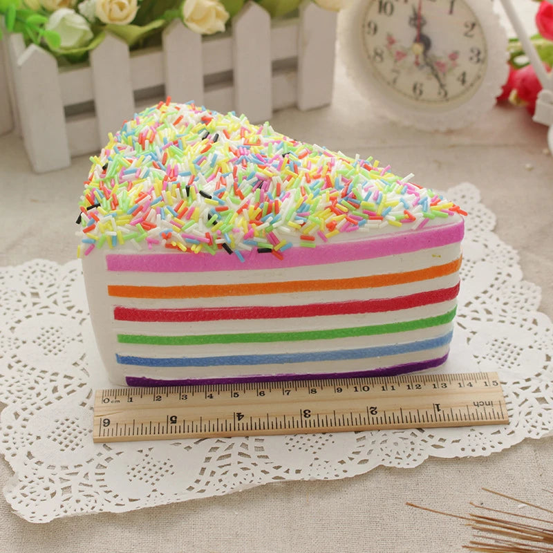 A colorful rainbow layer cake with striped frosting and topped with multicolored sprinkles, placed next to a ruler.
