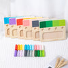 A set of wooden color matching blocks in various colors arranged in a row on a white surface.