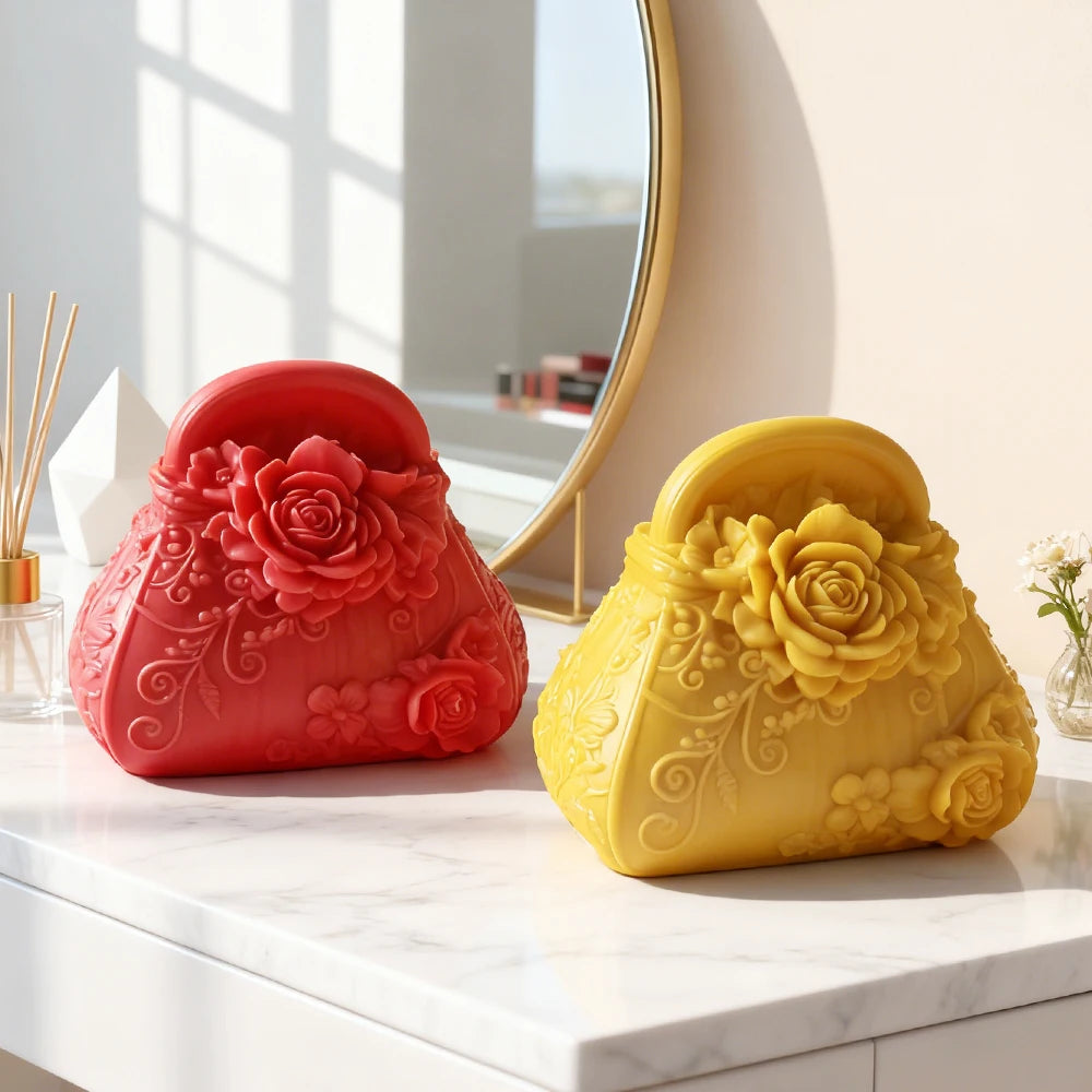A red silicone mold shaped like a rose is next to a yellow silicone mold shaped like a rose on a white marble surface.