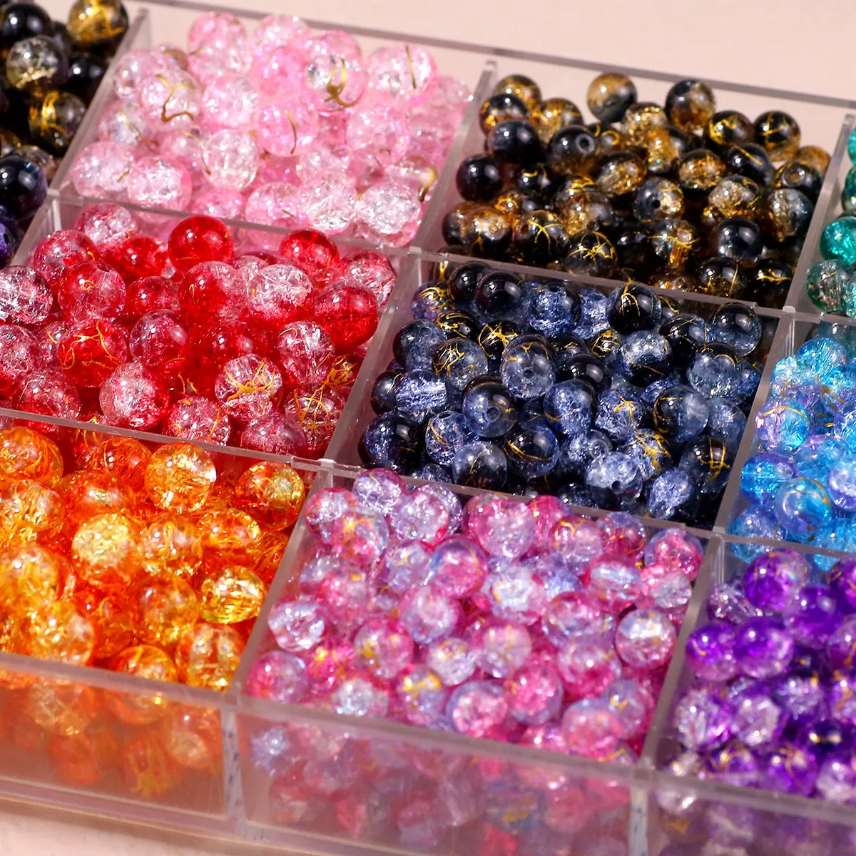A collection of gradient crystal glass beads with a golden crackle finish in various vibrant colors arranged in a clear plast
