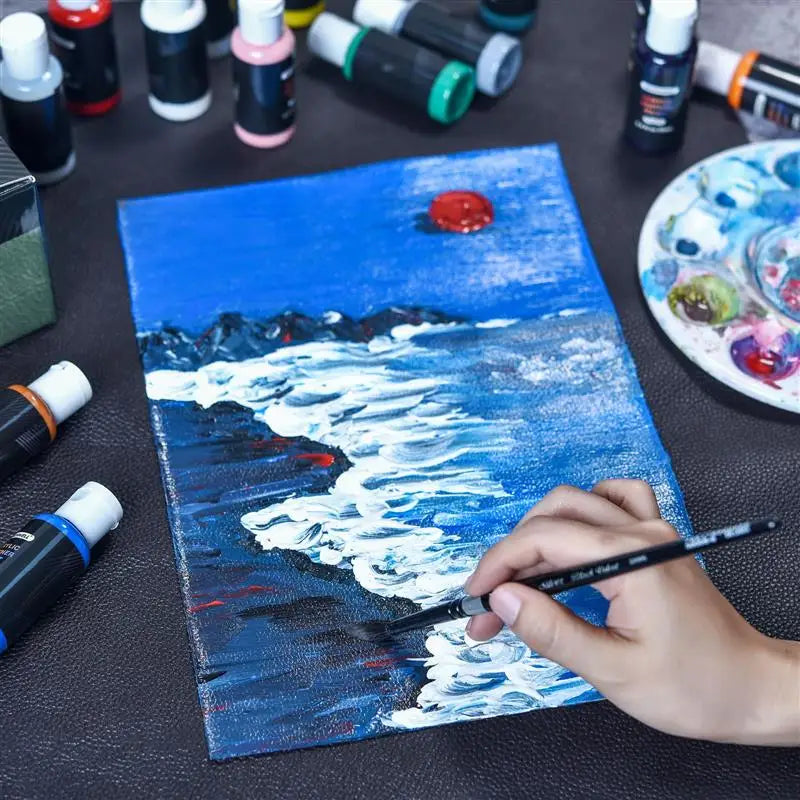 A hand paints a vibrant blue and white seascape on a canvas using an acrylic paint set.