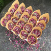 Dried rose petal confetti in natural pink and purple hues arranged in paper cups.