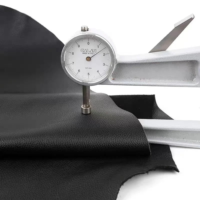 A silver leather gauge is shown next to a piece of black cowhide leather with a lychee texture.