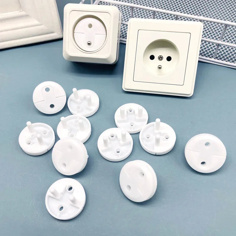 A collection of white rotating socket safety covers for baby proofing, including various sizes and shapes.