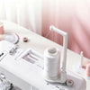 A white vertical sewing machine spool holder with a thread guide is shown on a white surface.